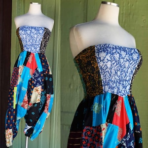 May include: A strapless patchwork jumpsuit in vibrant colors, including blue, red, and black. The top features a blue floral print and a brown patterned panel. The bottom has a harem pant style with a mix of patterned fabric patches.