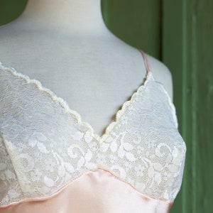 May include: A pink satin slip with white lace trim. The lace has a floral pattern.