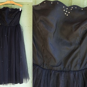 Puede incluir: Un vestido de tul negro sin tirantes con un corpiño de cuentas y un escote festoneado. El vestido tiene una falda completa y está adornado con pequeñas lentejuelas dispersas.