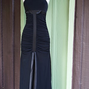 May include: A black, floor-length, sleeveless dress with a satin ribbon detail and a ruched bodice.