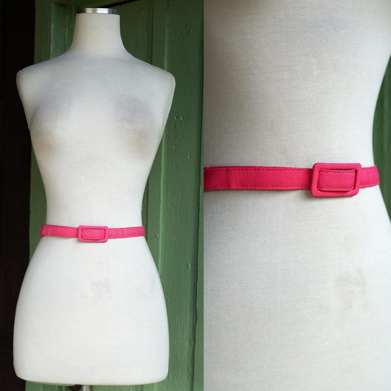 K&ouml;nnte beinhalten: Ein leuchtend pinkfarbener Stoffg&uuml;rtel mit einer rechteckigen Schnalle. Der G&uuml;rtel wird an einem wei&szlig;en Mannequin gezeigt.