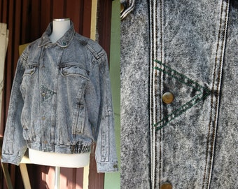 May include: A grey acid wash denim jacket with a zip closure, two flap pockets, and a green stitched detail on the front.