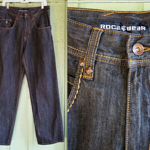 Peut inclure: Jean en denim fonc&eacute; avec des coutures jaunes et un logo Rocawear sur la poche arri&egrave;re.