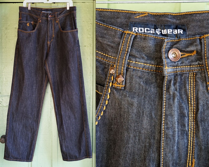 Peut inclure: Jean en denim fonc&eacute; avec des coutures jaunes et un logo Rocawear sur la poche arri&egrave;re.