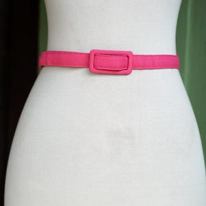 K&ouml;nnte beinhalten: Ein rosa Stoffg&uuml;rtel mit einer rechteckigen Schnalle.