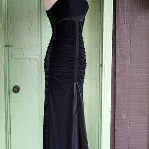 May include: A black, floor-length, sleeveless dress with a ruched bodice and a satin skirt.