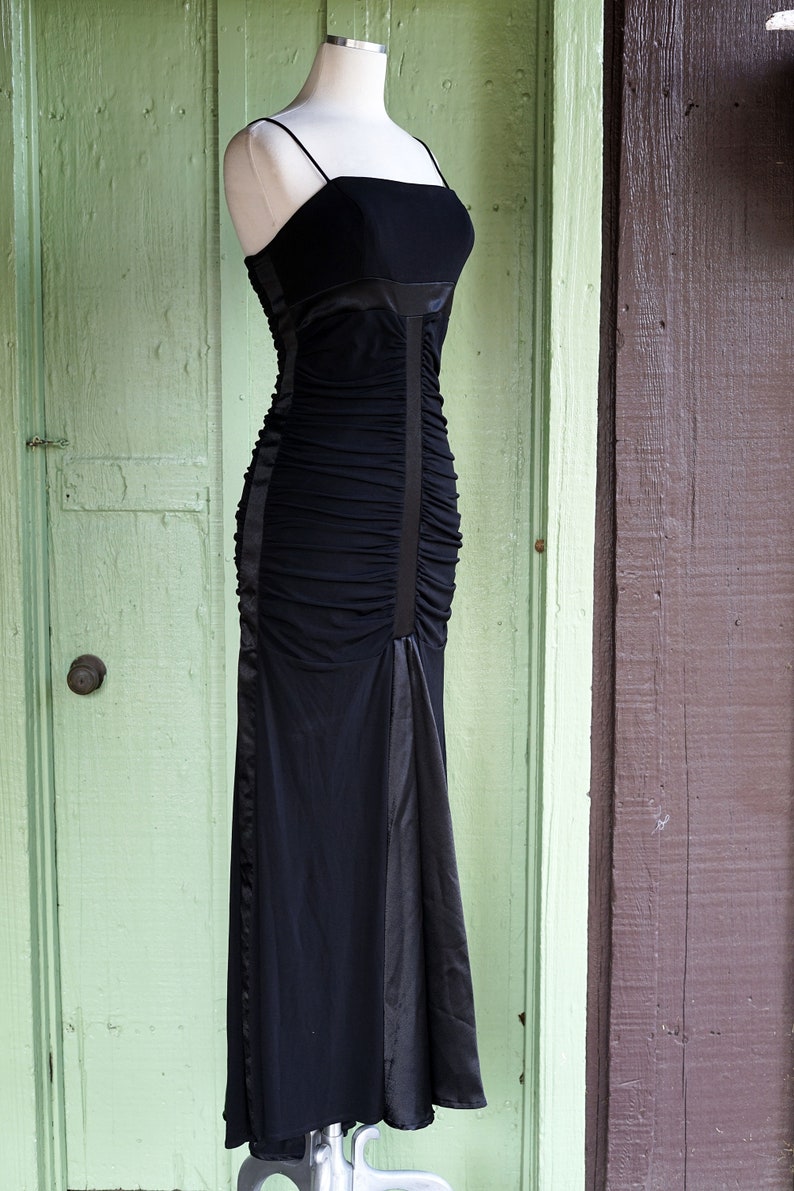 May include: A black, floor-length, sleeveless dress with a ruched bodice and a satin skirt.