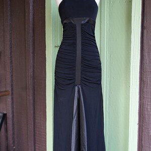 May include: A black floor-length dress with a ruched bodice and a satin skirt. The dress has a simple, elegant design and is perfect for a formal occasion.