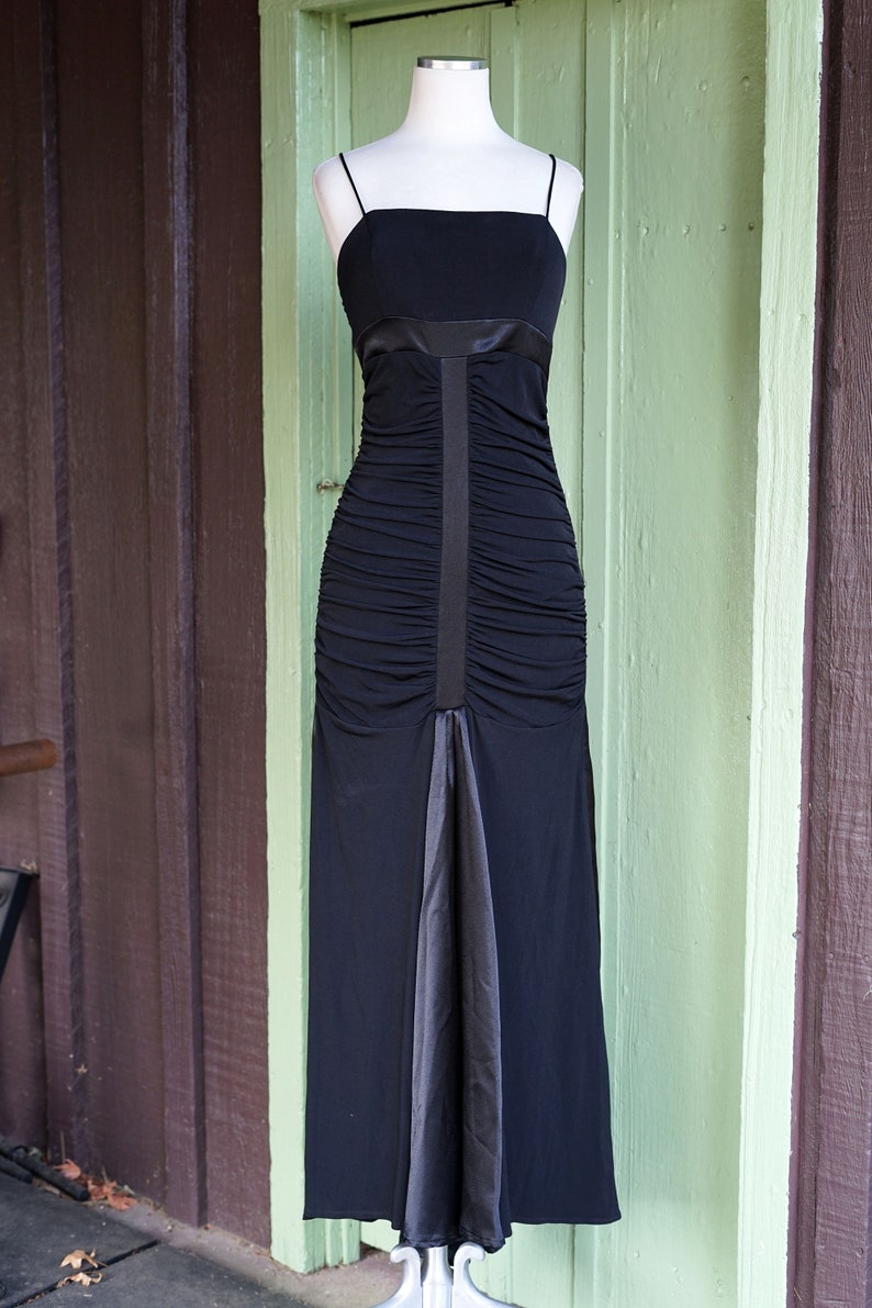 May include: A black floor-length dress with a ruched bodice and a satin skirt. The dress has a simple, elegant design and is perfect for a formal occasion.