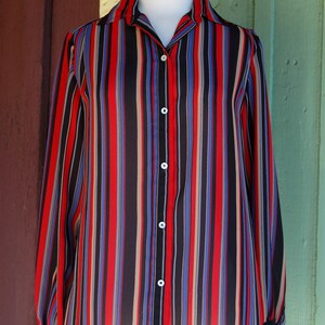 May include: A long-sleeved button-down shirt with vertical stripes in red, blue, black, and beige.
