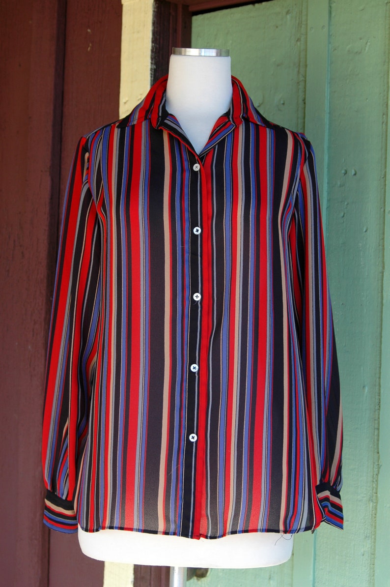 May include: A long-sleeved button-down shirt with vertical stripes in red, blue, black, and beige.