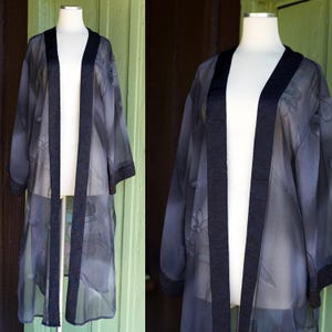 May include: A white ceramic mug with a black handle and the text "But First, Coffee" in a black, bold font. The mug is on a white surface. The mug is 4 inches tall.