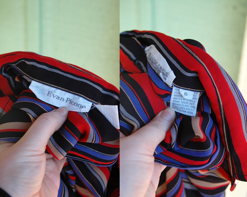 May include: A black, red, blue, and tan striped blouse with a white label that reads "Evan Picone" and another white label with care instructions. The care instructions include "Machine wash cold, gentle cycle, do not bleach, tumble dry low, warm iron."