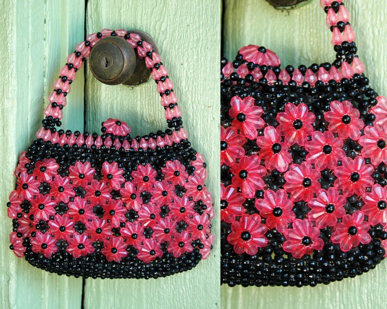 May include: A small pink and black beaded purse with a flower design. The purse has a top handle and is made of plastic beads.
