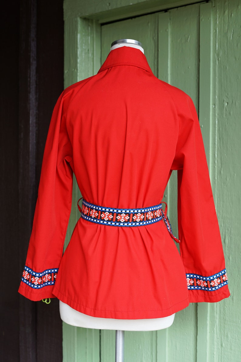 Puede incluir: Una camisa roja de manga larga con un cintur&oacute;n y pu&ntilde;os con estampado geom&eacute;trico. La camisa est&aacute; en un maniqu&iacute; blanco.