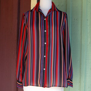 May include: A long-sleeved button-down shirt with vertical stripes in red, black, blue, and beige.