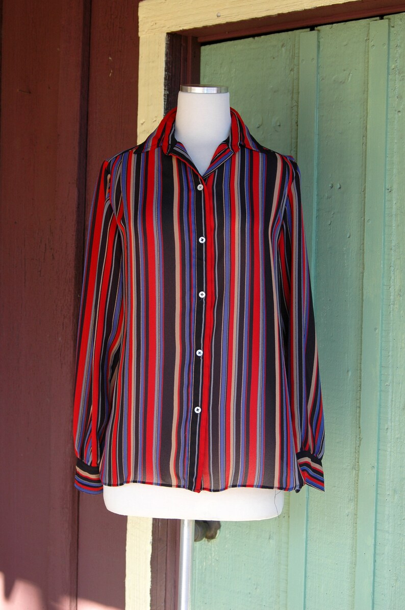 May include: A long-sleeved button-down shirt with vertical stripes in red, black, blue, and beige.