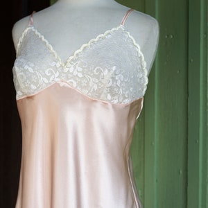 May include: A pale pink satin slip dress with a white lace trim around the neckline.