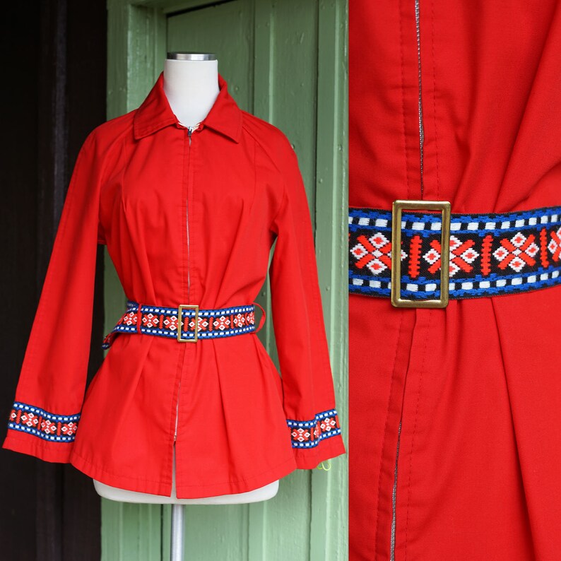 Puede incluir: Chaqueta roja con cremallera con un cintur&oacute;n de estampado geom&eacute;trico y ribetes a juego en los pu&ntilde;os. La chaqueta tiene un cuello cl&aacute;sico y mangas largas.