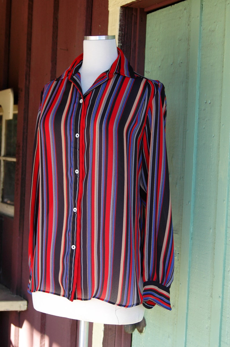 May include: A long-sleeved button-down shirt with vertical stripes in red, blue, black, and beige.