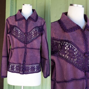 May include: A purple suede jacket with crocheted detailing. The jacket has a button-up front and long sleeves.