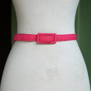 K&ouml;nnte beinhalten: Ein rosa Stoffg&uuml;rtel mit einer rechteckigen Schnalle.