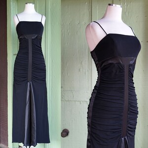 May include: A black, floor-length, strapless dress with a ruched bodice and a satin trim. The dress is on a white mannequin.