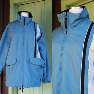 May include: A light blue jacket with a zipper closure and two pockets. The jacket has white and black stripes on the sleeves.