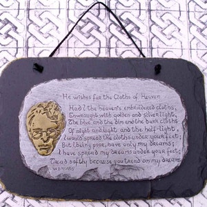 Può includere: Una placca di ardesia con una poesia di W.B. Yeats, "He wishes for the Cloths of Heaven." La poesia è stampata su una superficie simile alla pietra con un'illustrazione dorata del viso di un uomo.
