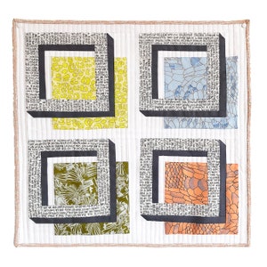 Peut inclure: Un carré de tissu blanc avec quatre cadres noirs, chacun contenant un tissu à motifs différent. Les cadres sont en tissu noir avec du texte blanc. Le texte dans les cadres dit "Unraveling the Land of Opportunity, Where the Spirit of Freedom Thrives".