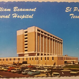May include: Vintage postcard featuring William Beaumont General Hospital in El Paso, Texas. The image shows a large, multi-story building with a tan facade and a flat roof, set against a clear blue sky. A parking lot filled with cars is in the foreground.