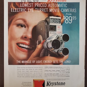 May include: A vintage advertisement for Keystone Electric Eye Turret Movie Cameras. The ad features a woman holding a Keystone camera and the text "NEW FROM Keystone LOWEST PRICED AUTOMATIC ELECTRIC EYE TURRET MOVIE CAMERAS from $89.95". The ad also includes a description of the camera's features and a tagline: "THE MIRACLE OF LIGHT ENERGY SETS THE LENS!"