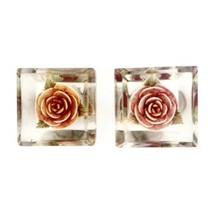 May include: A pair of clear square earrings with a pink rose design inside each earring.