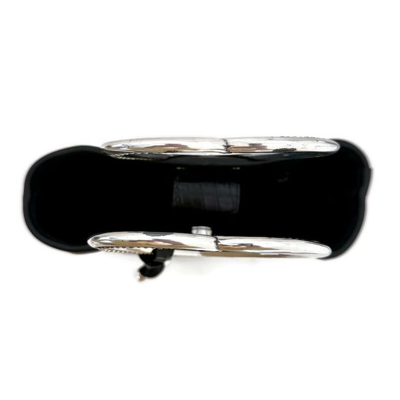 Pu&ograve; includere: Borsa a mano in pelle nera con dettagli in metallo argentato. La borsa ha due grandi manici circolari.