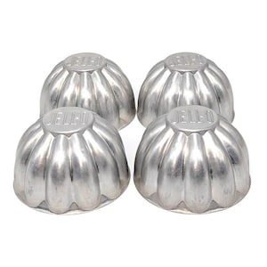 May include: Four vintage silver-colored Jell-O molds. Each mold has a fluted, flower-like shape with the word "JELL-O" embossed on the top. These classic molds are perfect for creating gelatin desserts and adding a touch of retro charm to your kitchen.