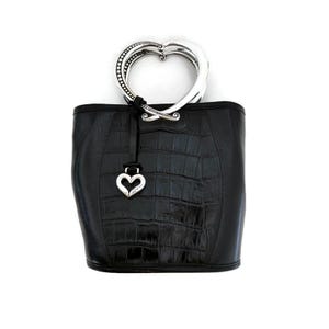 Pu&ograve; includere: Borsa a mano in pelle nera con manico a forma di cuore in argento e un ciondolo a forma di cuore in argento.