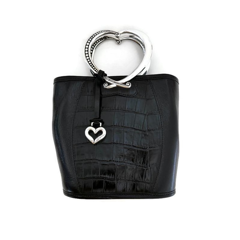 Pu&ograve; includere: Borsa a mano in pelle nera con manico a forma di cuore in argento e un ciondolo a forma di cuore in argento.