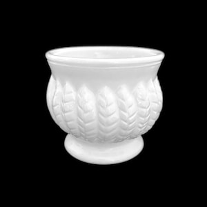 May include: White ceramic planter with a leaf design. The planter has a rounded base and a wide opening.