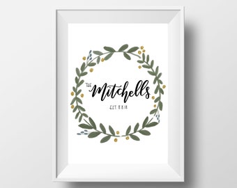 May include: A white framed print with a green leafy wreath with gold glitter accents. The wreath surrounds the text "The Mitchells Est. 8.8.18".