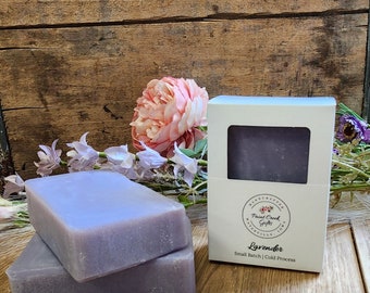 May include: Two bars of lavender-colored soap stacked on top of each other. The soap is packaged in a white box with the text "Handcrafted Paint Creek Gifts" and "Lavender Small Batch | Cold Process".