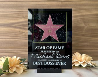 May include: A black acrylic plaque with a pink star and the text "STAR OF FAME PRESENTED TO Michael Torres COMMISSION FOR THE AWARD OF BEST BOSS EVER".