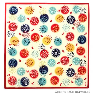 Op de afbeelding: Een wit vierkant van katoenen stof met een rode rand. De stof is bedrukt met een herhalend patroon van kleurrijke vuurwerk in rood, geel, blauw en groen. De tekst "Goldfish and Fireworks" is in zwart gedrukt aan de onderkant van de stof.