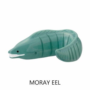 May include: A teal ceramic moray eel figurine with a white mouth and teeth. The eel has a curved body with ribbed detailing and a small black eye. The text "MORAY EEL" is below the figurine.