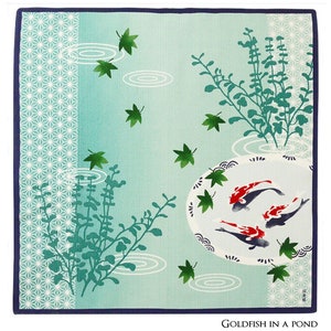 Op de afbeelding: Een blauw en groen vierkant van stof met een ontwerp van goudvissen die zwemmen in een vijver met waterlelies en bladeren. De tekst "Goldfish in a Pond" is onderaan het vierkant gedrukt.