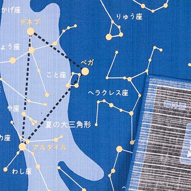 May include: A blue fabric featuring a white and light blue star map with constellations and Japanese text. The design includes the Summer Triangle, Vega, Deneb, and Altair, connected by lines, with a striped blue and white border on the right side.