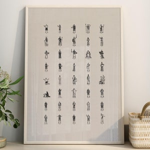 Puede incluir: Una impresión en blanco y negro enmarcada de una cuadrícula de figuras de palo en varias poses. La impresión está colgada en una pared blanca sobre un estante de madera con una cesta tejida, un cuenco pequeño y una pila de libros.