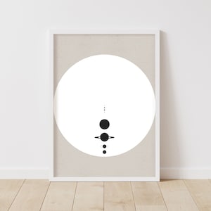 May include: A black and white minimalist print of a circle with a stylised solar system inside. The print is framed in a white frame and is hanging on a white wall.