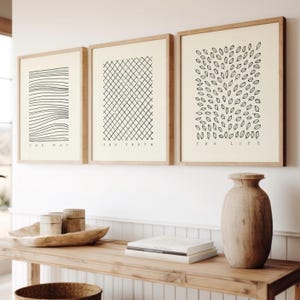 Puede incluir: Tres impresiones artísticas enmarcadas con diseños minimalistas en blanco y negro. Las impresiones presentan patrones abstractos y las palabras "THE WAY", "THE TRUTH" y "THE LIFE". Una mesa de madera con objetos decorativos está en primer plano.