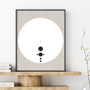 May include: A black and white minimalist print of a solar system with a white circle in the background and a beige frame.