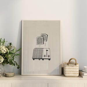 Puede incluir: Una ilustraci&oacute;n en blanco y negro de dos rebanadas de pan que salen de una tostadora. La ilustraci&oacute;n est&aacute; sobre un fondo beige y enmarcada en un marco blanco.